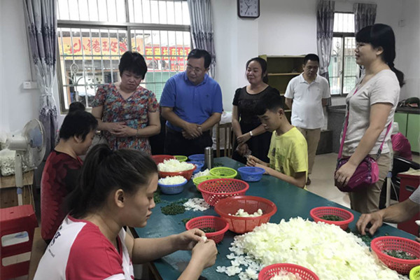 图为黎理事长（左二）和冼副理事长（左一）一行实地考察康园中心的庇护工场