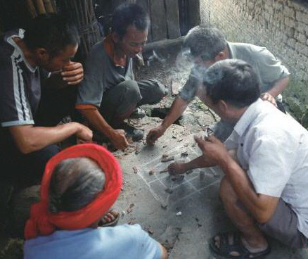 阴雨天,三五瑶民聚在一起玩瑶族传统“赶猪棋”。
